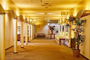A hotel corridor with a central bench, columns, and a potted plant. - Ageo Tobu Hotel (Ageo)