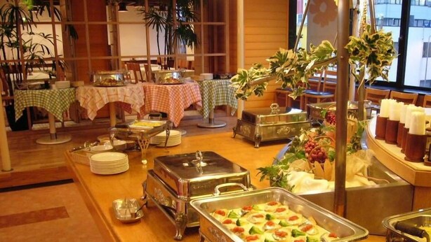 A buffet setup with various food stations, including a tray of vegetables and a cheese platter, in a room with wooden flooring and potted plants. - Ageo Tobu Hotel (Ageo)