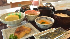 A table with various dishes, including a bowl of soup, a plate of fish, and several small bowls with different foods.