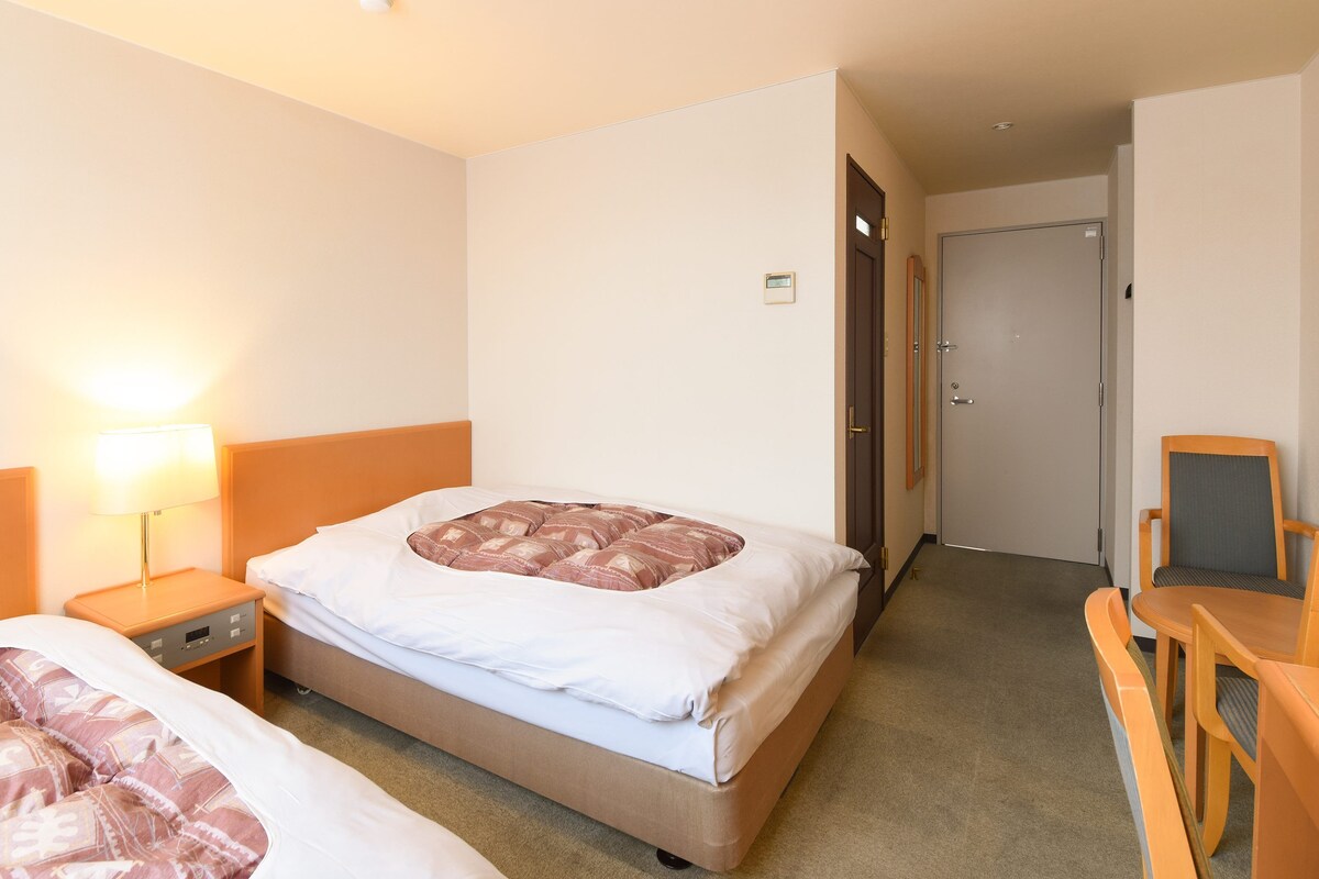 Ein Hotelzimmer mit zwei Betten, einem Schreibtisch und einem Stuhl.