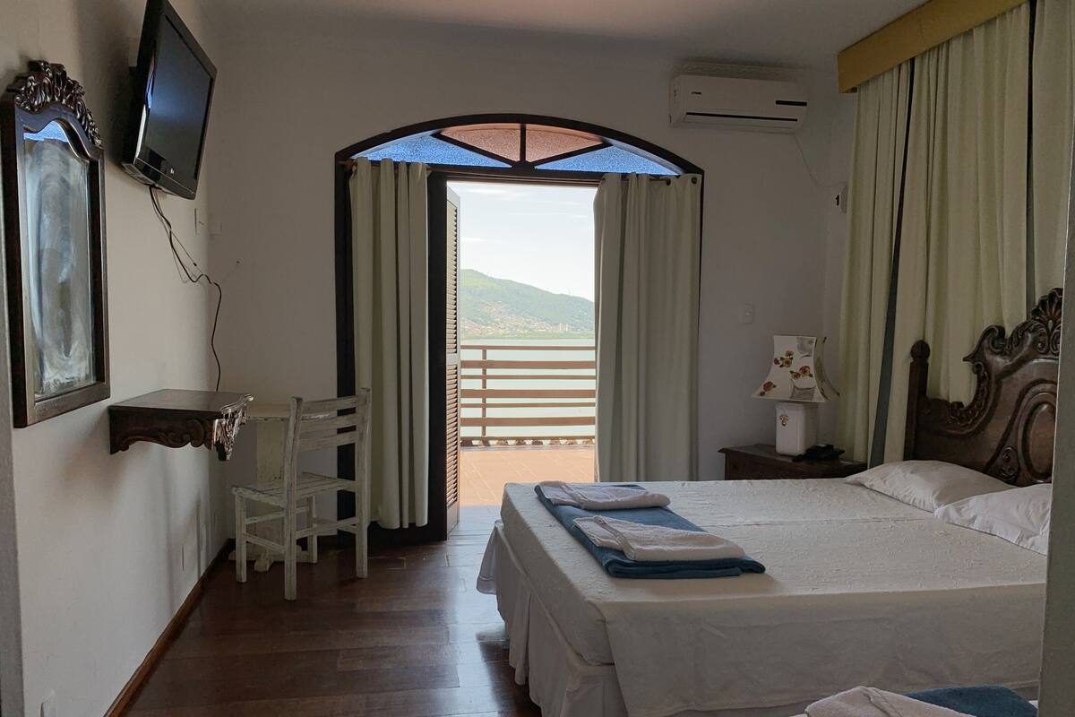 Ein Hotelzimmer mit Bett, Schreibtisch, Sessel, Fernseher und Blick ins Freie.