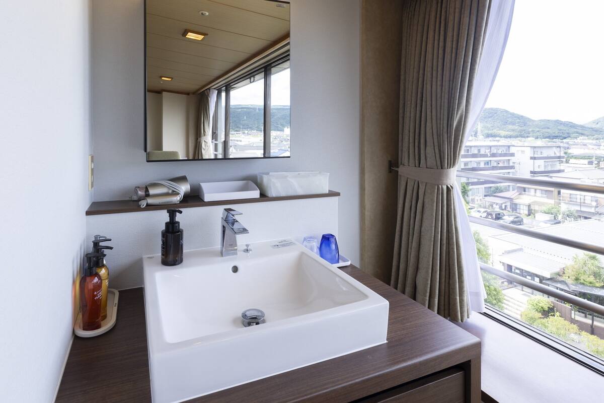 A hotel bathroom with a white sink, mirror, and shelves with toiletries.