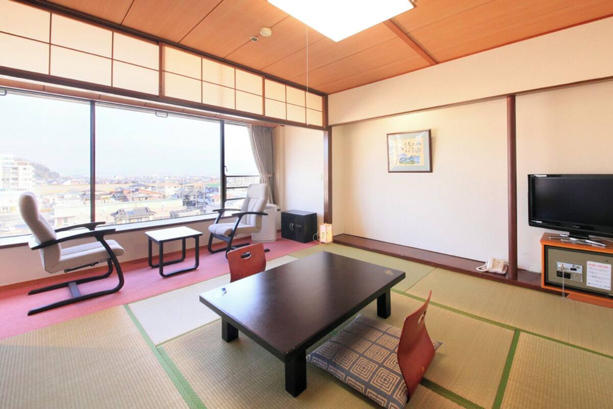 A room with tatami mats, a television, a sofa, and a table.