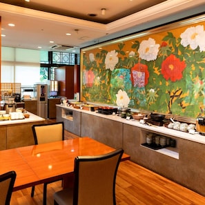 Un restaurant amb barra de buffet, zona de seients i una paret decorativa amb motius florals.