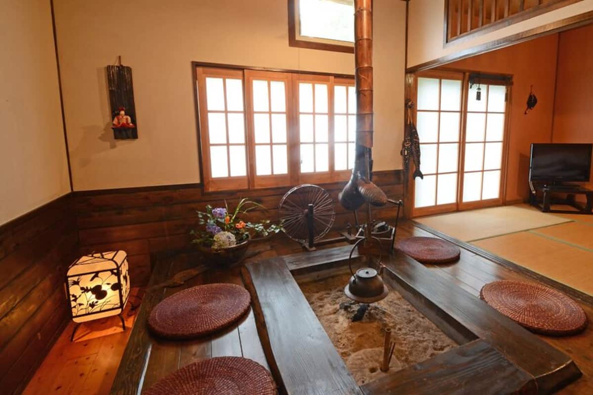 A traditional Japanese room with tatami flooring, a shoji screen, a tatami mat table, a tea kettle, and a lantern.