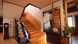 A wooden staircase leading to a landing, a large decorative mirror, and a bookshelf with various items. - Shikisai no Sato Manyuu (Kirishima)