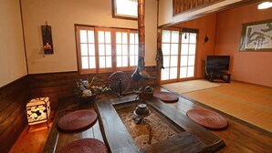 A traditional Japanese room with tatami flooring, a shoji screen, a tatami mat table, a hanging tatami mat, a traditional Japanese lantern, and a television. - Shikisai no Sato Manyuu (Kirishima)