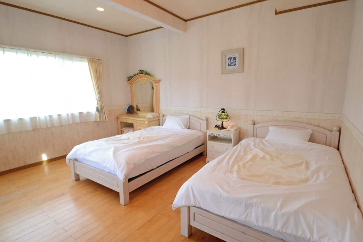 A bedroom with two single beds, a dresser, a nightstand, a mirror, and a framed picture on the wall.
