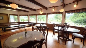 A restaurant interior with wooden floors, round tables, and benches. - Shikisai no Sato Manyuu (Kirishima)