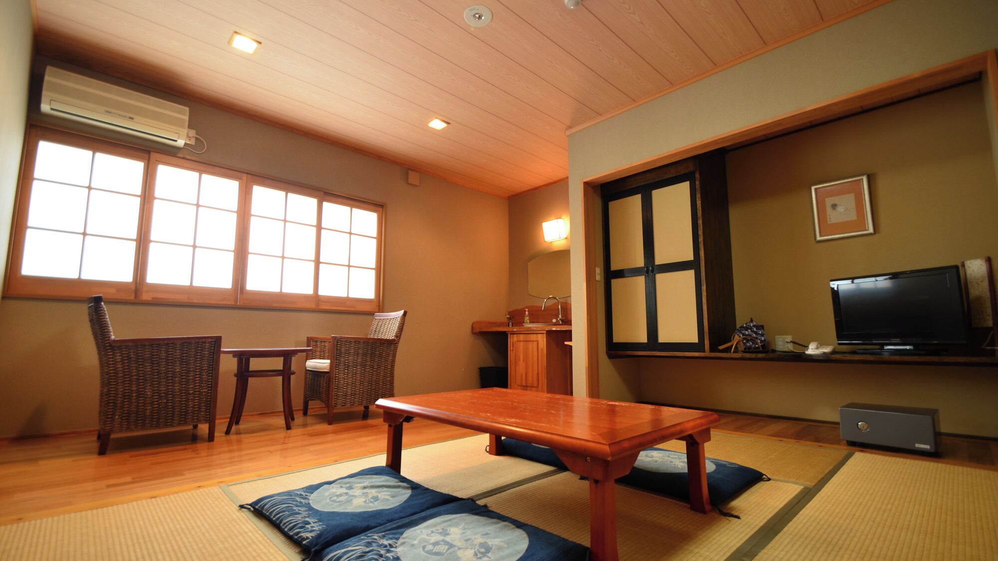 A traditional Japanese-style room with tatami mats, a low table, a television, and a cabinet.