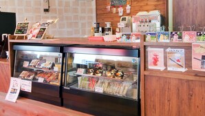 A café with wooden interior, a menu board, refrigerated display cases, and a coffee machine. - Shikokuya (Saijo)