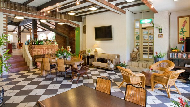 A spacious lobby with a checkered floor, a bar area with bottles, a sofa, and wicker chairs. - Casual Seagull (Nishiizu)