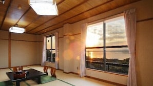 Una habitación japonesa tradicional con suelo de tatami, una mesa baja y ventanas amplias con cortinas.