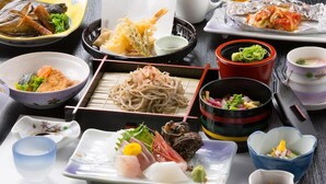 A variety of Japanese dishes including sushi, sashimi, and noodles, served on a wooden table. - New Marutaso (Kyotango)