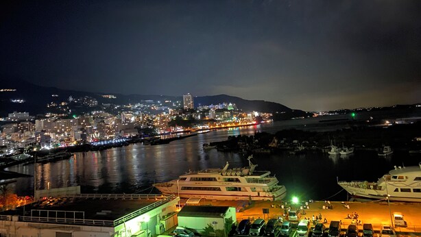 A nighttime cityscape with a river, boats, and a dock area. - Atami Minoya Hotel (Atami)