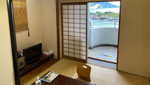A traditional Japanese room with tatami flooring, a sliding door, a television, and a view of a harbor. - Atami Minoya Hotel (Atami)