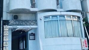 A multi-story building with balconies, a staircase leading to the entrance, and a Coca-Cola vending machine. - Atami Minoya Hotel (Atami)