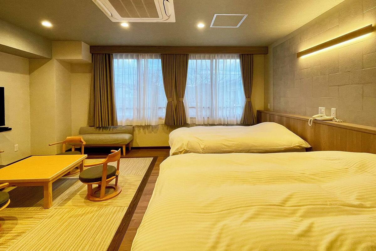 A hotel room with a bed, a desk, a chair, a television, and a window with curtains.