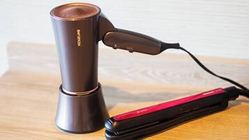 A hair straightener and a cylindrical device on a wooden surface.