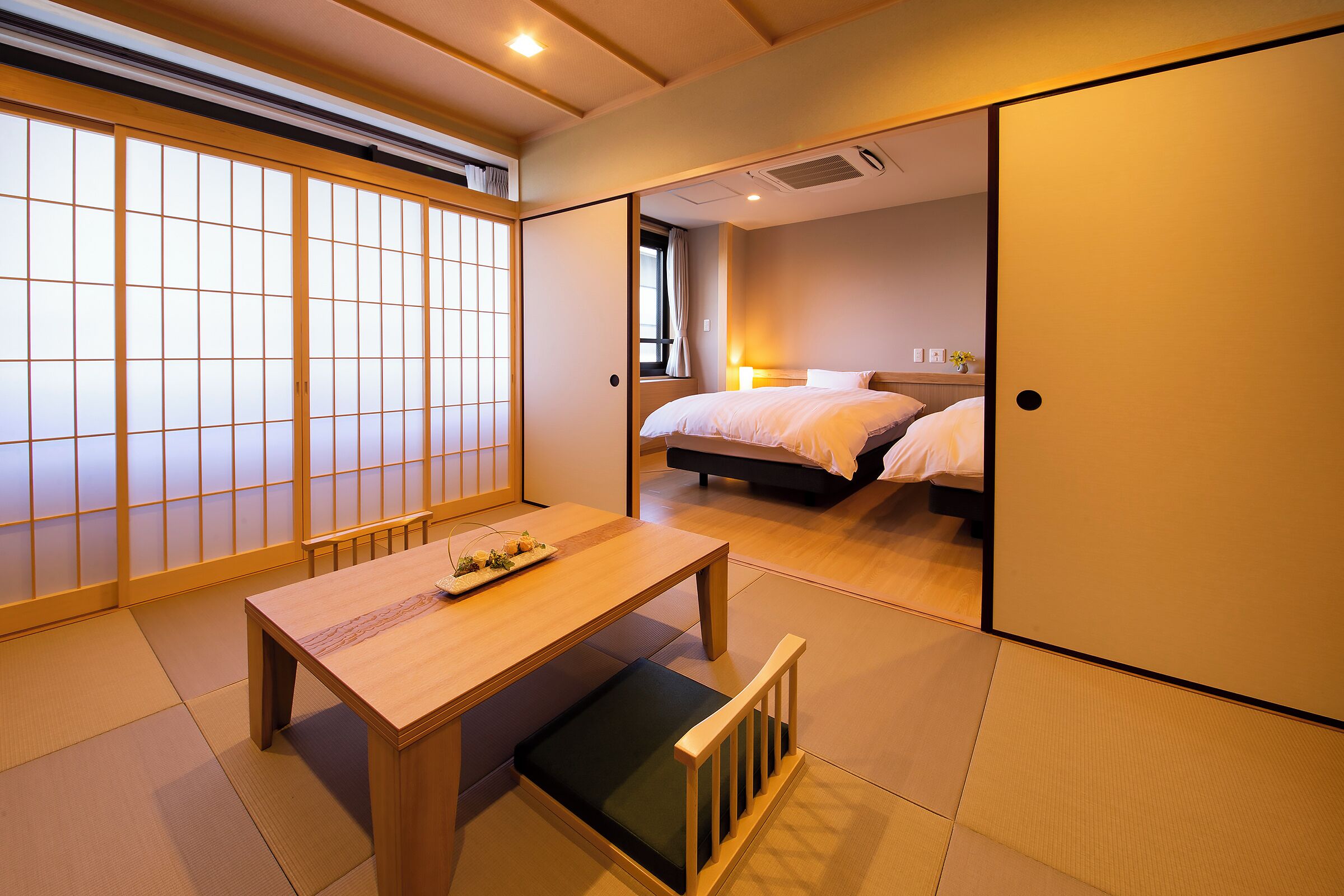 A traditional Japanese-style room with tatami flooring, a low wooden table, and a sliding shoji screen door.