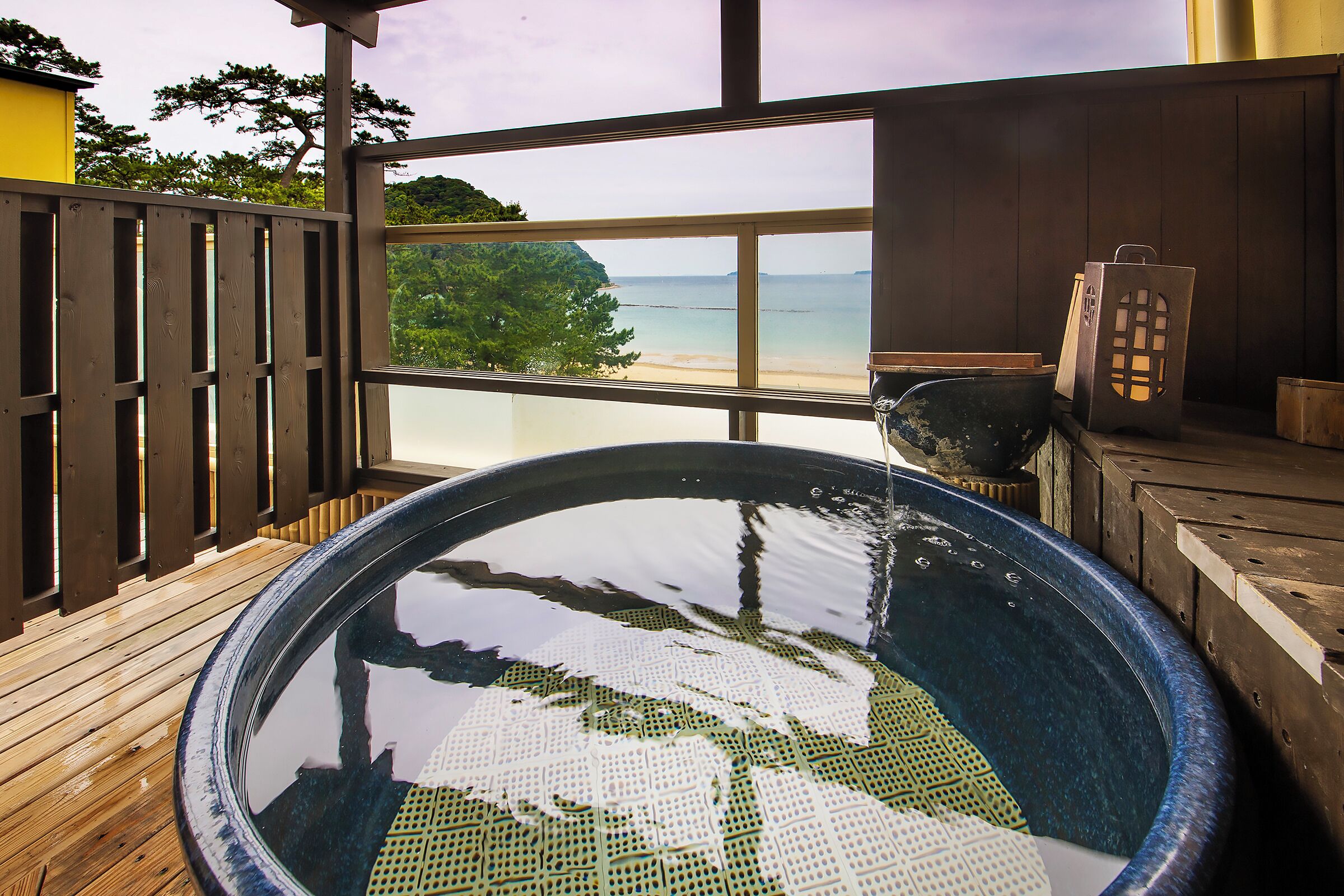 Un bain à remous avec une terrasse en bois et vue sur la plage.