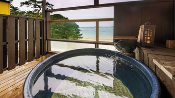 Un bain à remous avec une terrasse en bois et vue sur la plage.