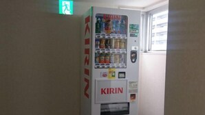 A vending machine labeled 'KIRIN' with various drink options, located in a hallway with a window and a door. - Kusatsu Estopia Hotel (Kusatsu (Shiga))