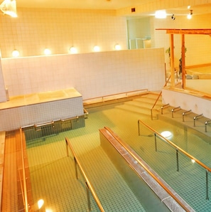 A swimming pool with multiple lanes, a changing room area, and a seating area with a wooden structure.