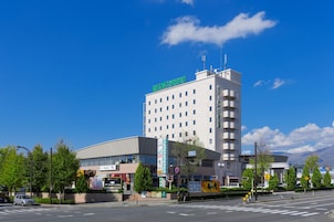 A multi-story hotel with a prominent sign on the roof, a large parking lot, and a clear blue sky.