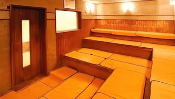 A room with wooden walls and a door, featuring a set of steps leading to a seating area with cushioned benches.