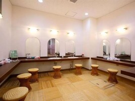 A hotel bathroom with multiple sinks, mirrors, and stools.