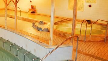 A traditional Japanese onsen with wooden benches and a stone bath area.