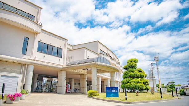 A hotel with a covered entrance, large pillars, and a signboard. - Isozaki Onsen Hotel New Hakuaki (Hitachinaka)