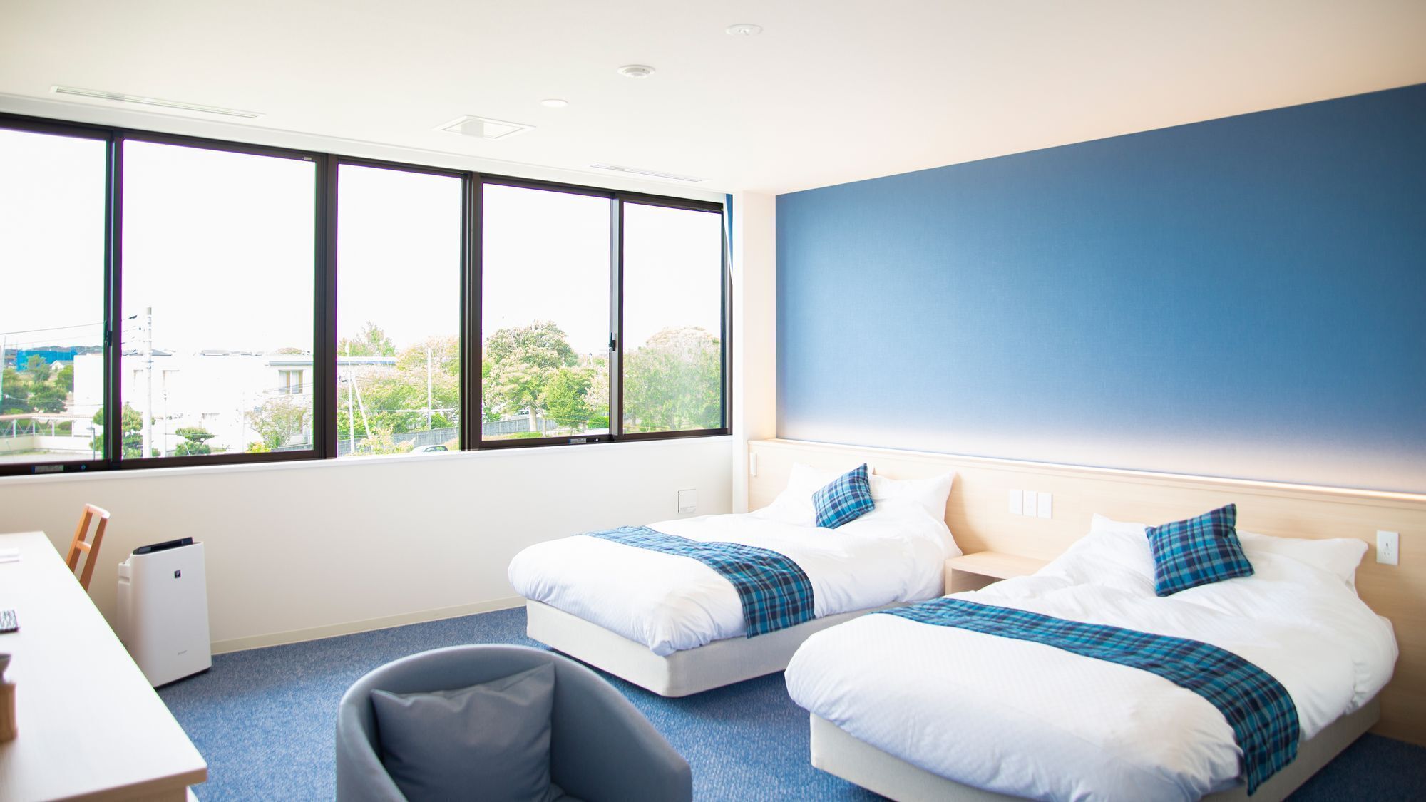 A hotel room with two beds, a desk, and a chair.