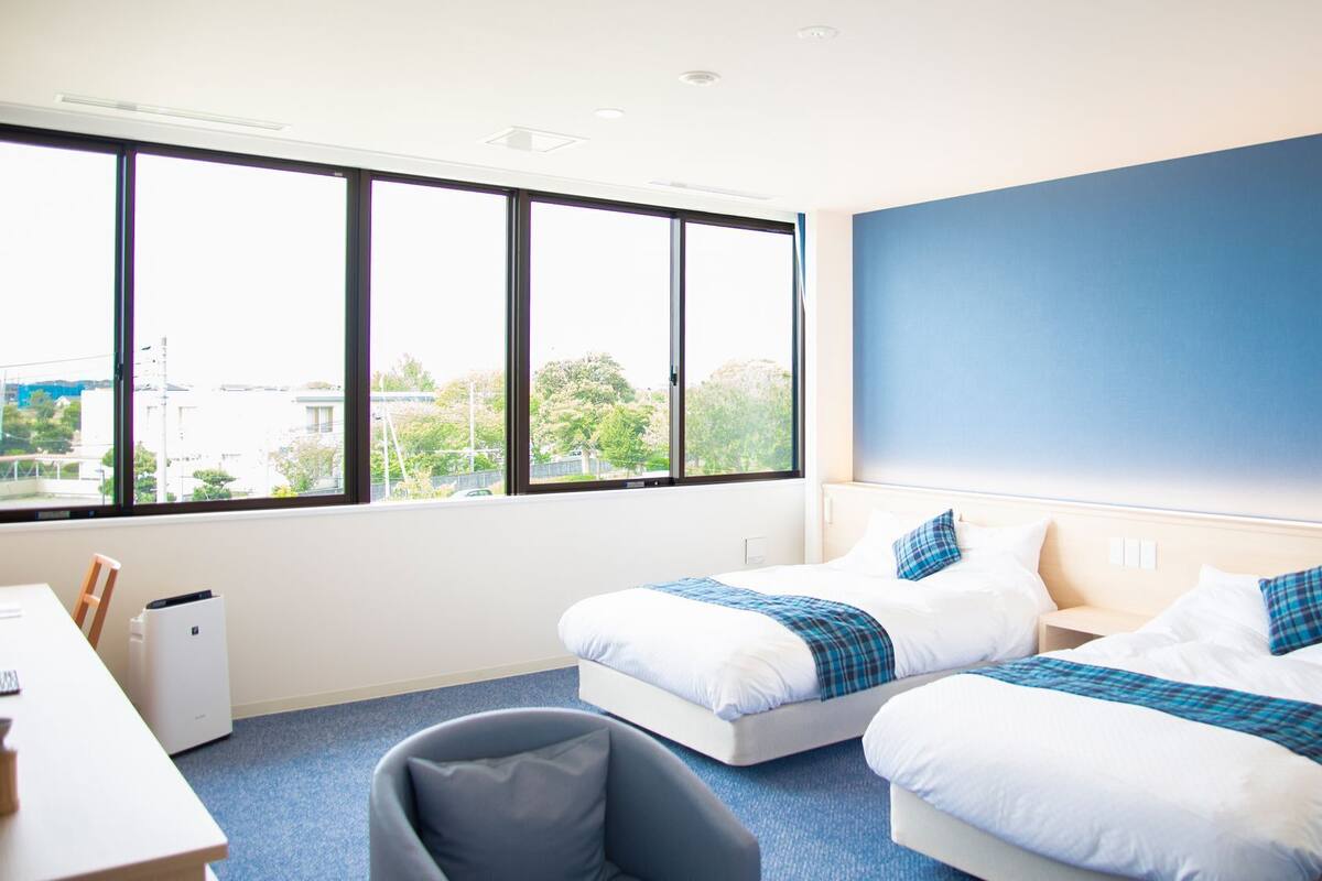A hotel room with two beds, a desk, and a chair.