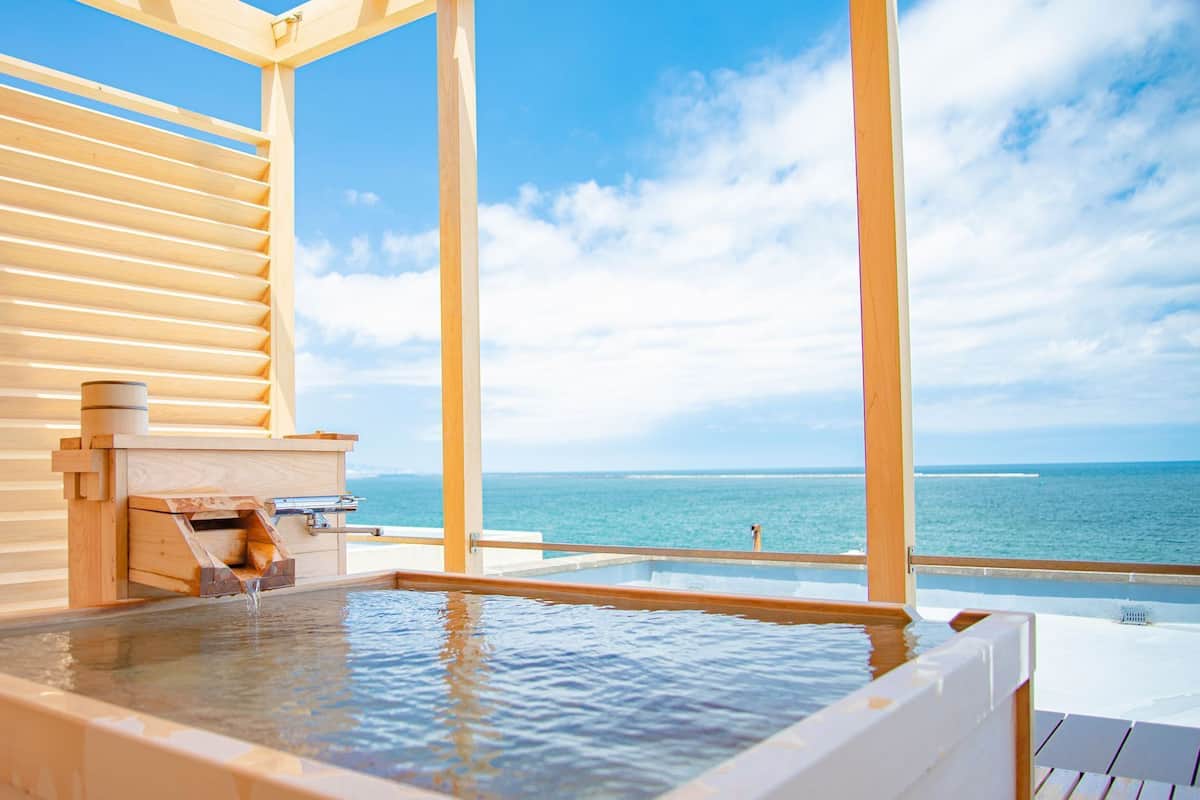 A wooden spa with a hot tub and a view of the ocean.