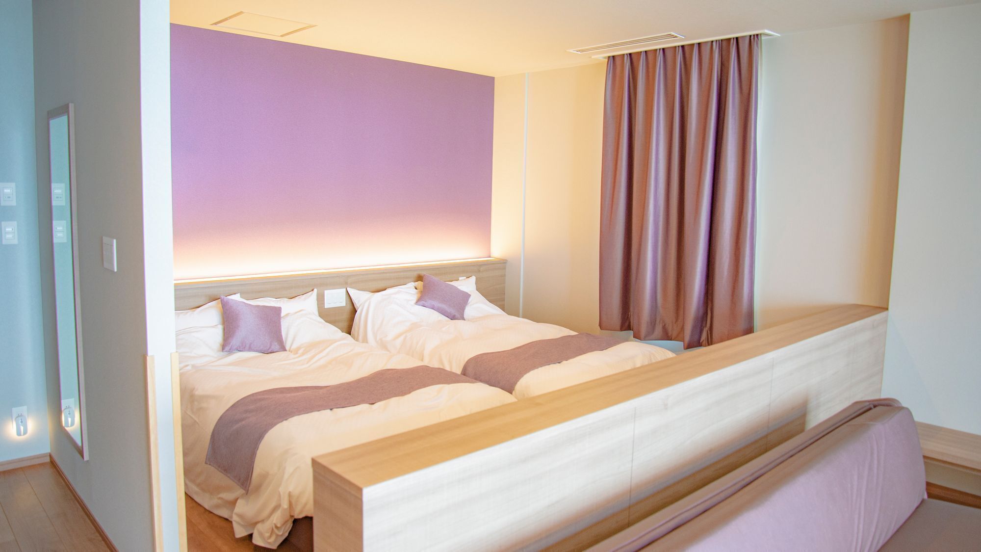 A double bed with a wooden headboard, a bedside table, and a window with curtains.