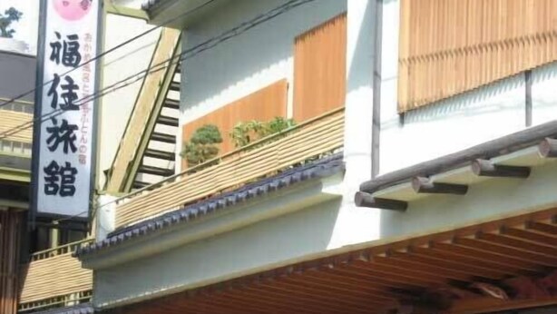 Un bâtiment avec une enseigne indiquant « 福住館 » et une voiture garée devant.