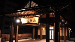 Une entrée d’immeuble avec une pergola en bois, une enseigne avec des caractères japonais et un sol carrelé.