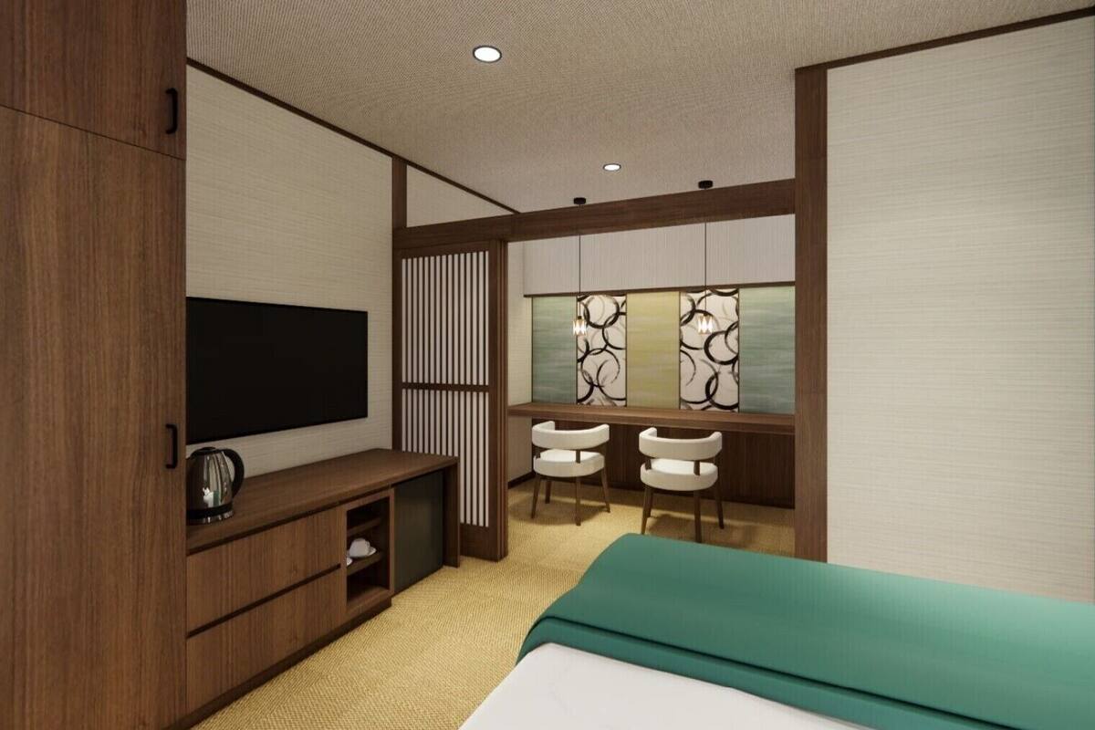 A modern bedroom with a bed, a TV, a desk with chairs, and a window with decorative panels.