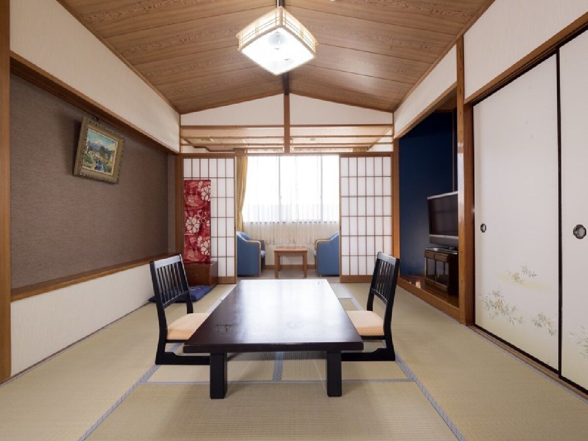 Una habitación japonesa tradicional con suelo de tatami, una mesa baja y paneles shoji.