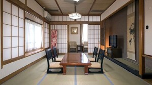A traditional Japanese room with tatami flooring, a low wooden table, and four chairs. - Izu Nagaoka Onsen Kkr Izu Nagaoka Chitoseso (Izunokuni)