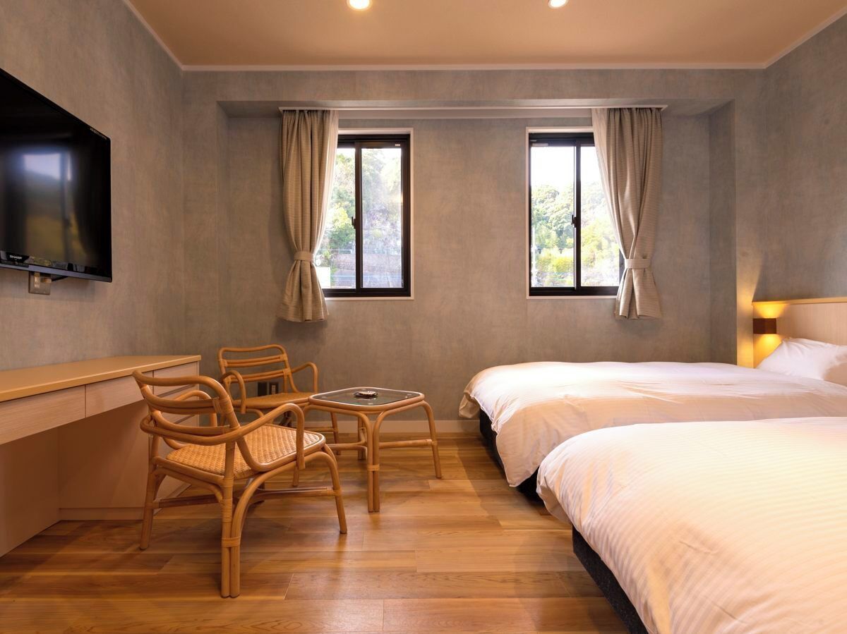 A hotel room with a bed, a desk, a chair, and a TV.