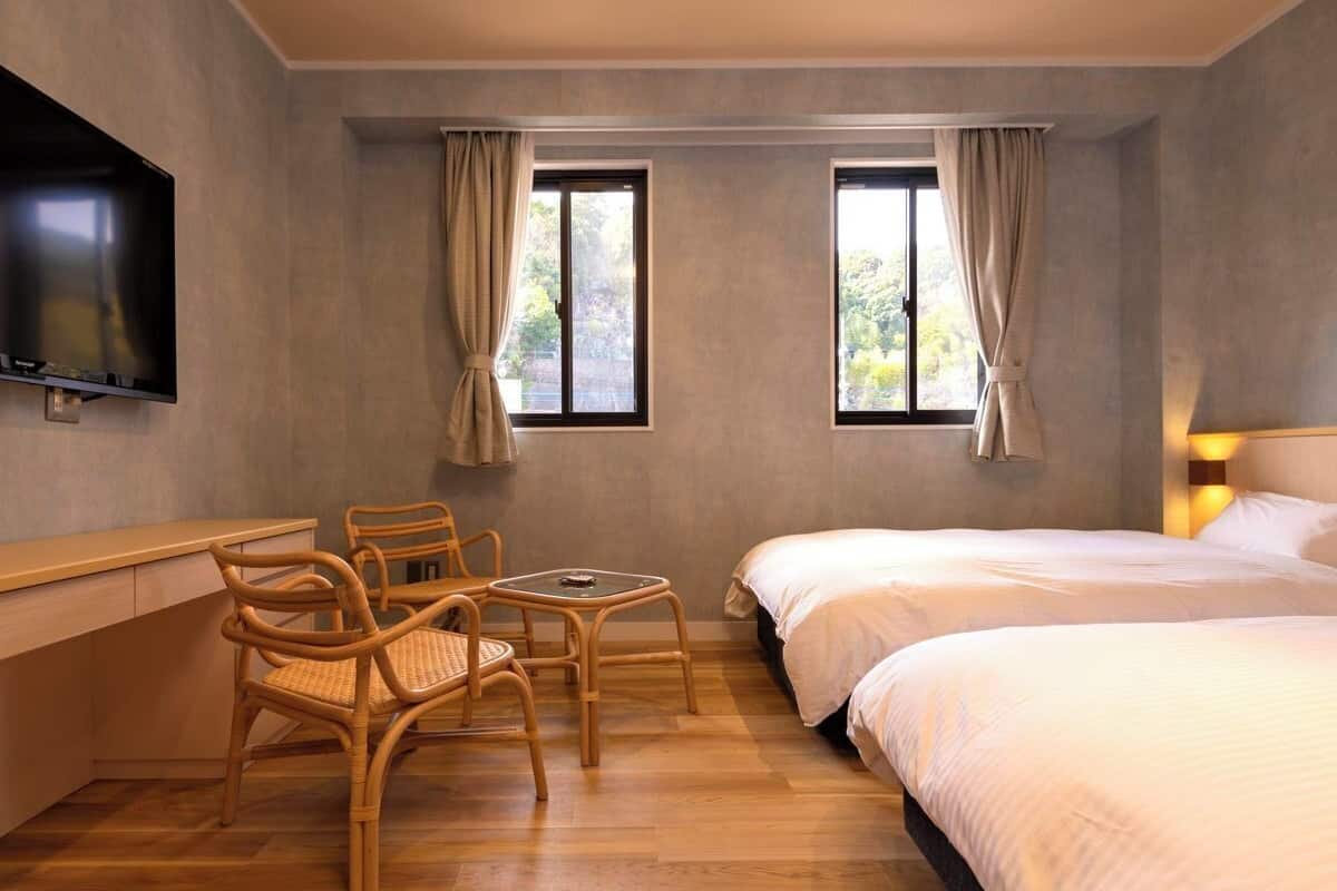 Ένα δωμάτιο ξενοδοχείου με ένα κρεβάτι, ένα γραφείο, μια καρέκλα και μια τηλεόραση.