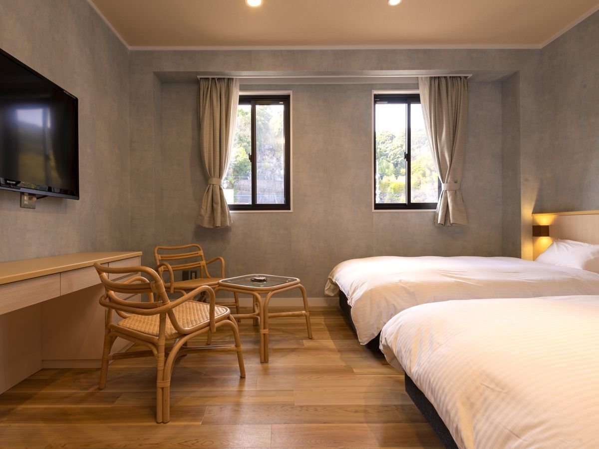 Una habitación de hotel con cama, escritorio, dos sillas y televisión.