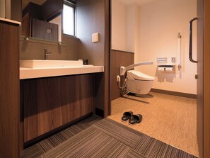 A modern bathroom with a sink, mirror, and toilet. - Izu Nagaoka Onsen Kkr Izu Nagaoka Chitoseso (Izunokuni)