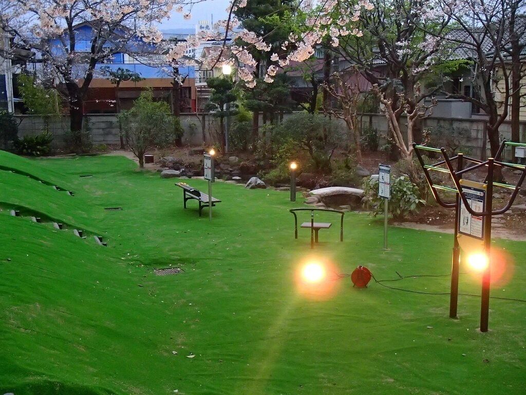 A park with green grass, benches, and a stone pathway.