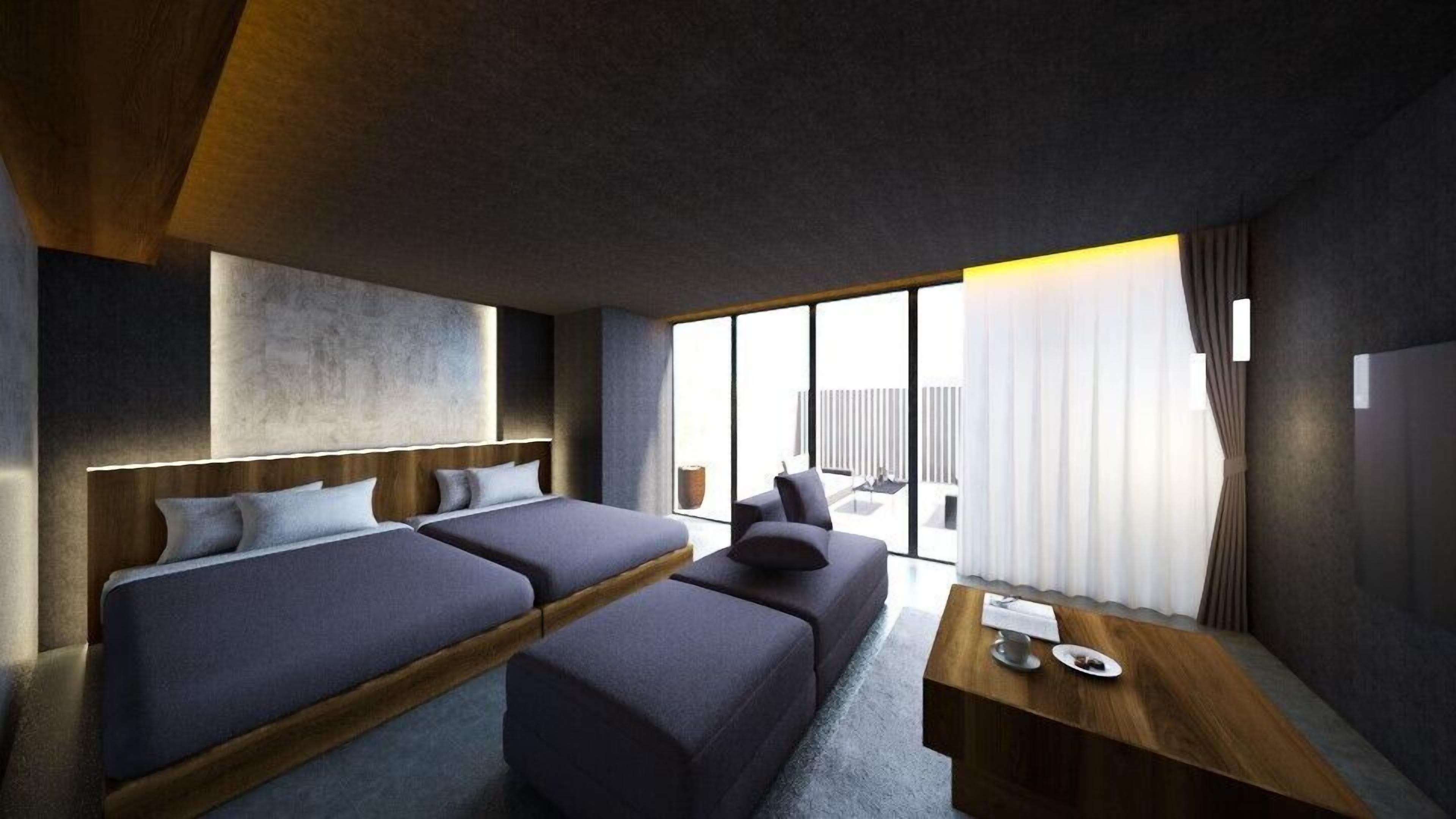 A modern hotel room with a large bed, a sofa, a small table, and a view of the outdoors.