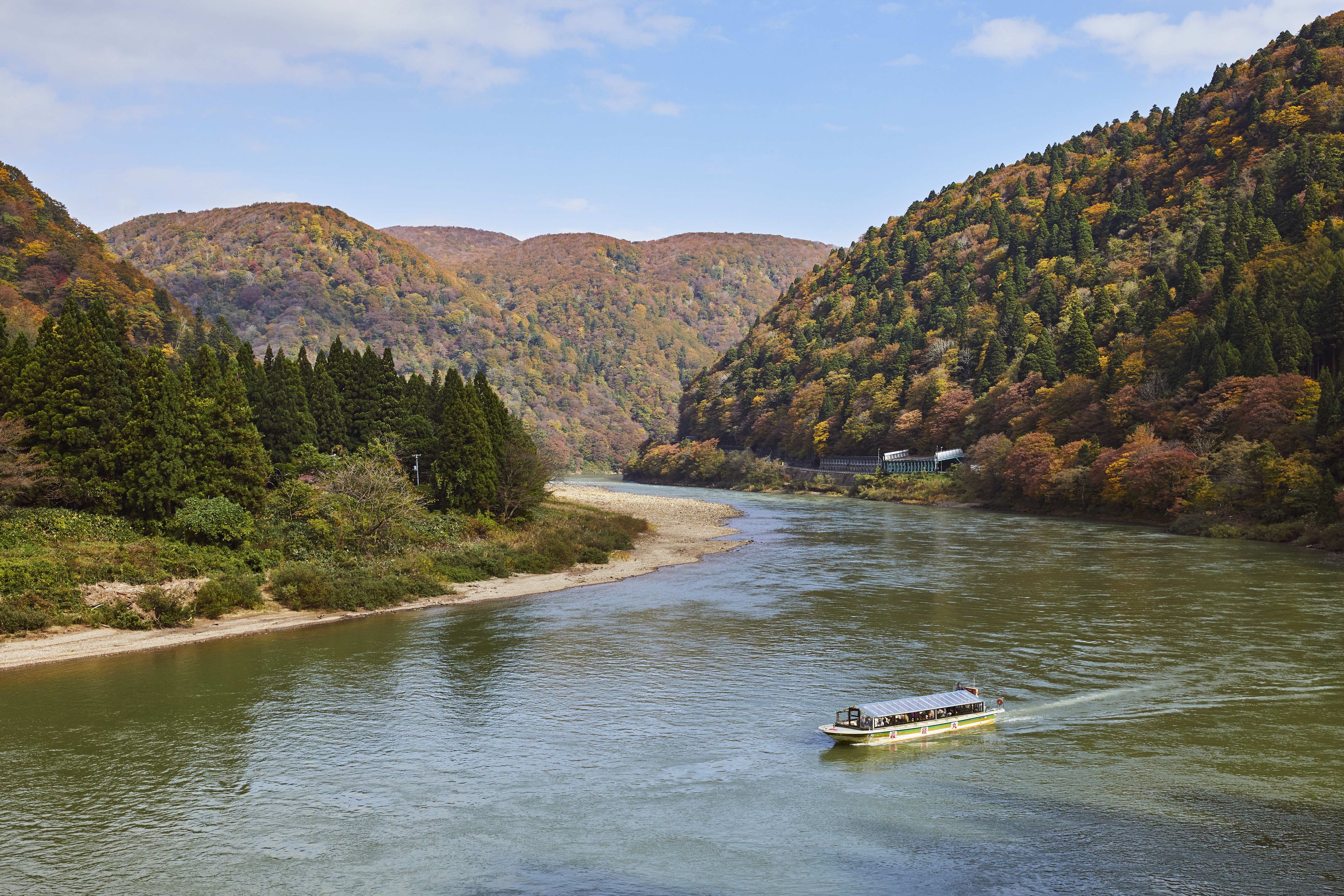 A river with a boat, surrounded by forested hills.