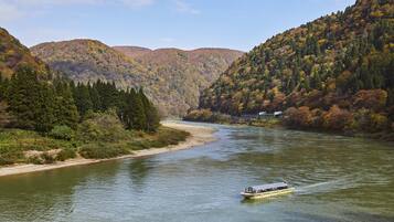 A river with a boat, surrounded by forested hills.